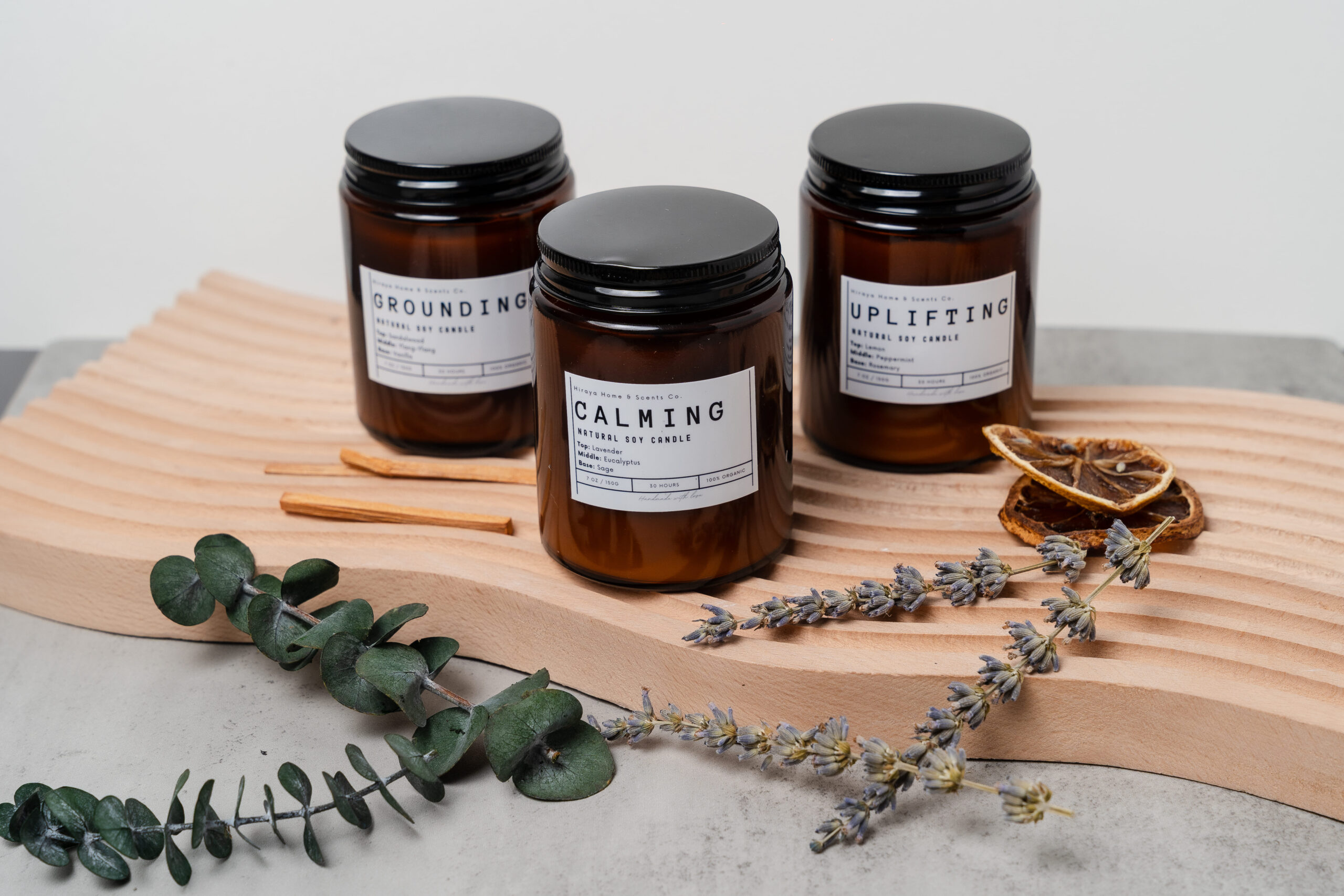 Group display of the Calming, Uplifting, and Grounding aromatherapy candles in amber jars.