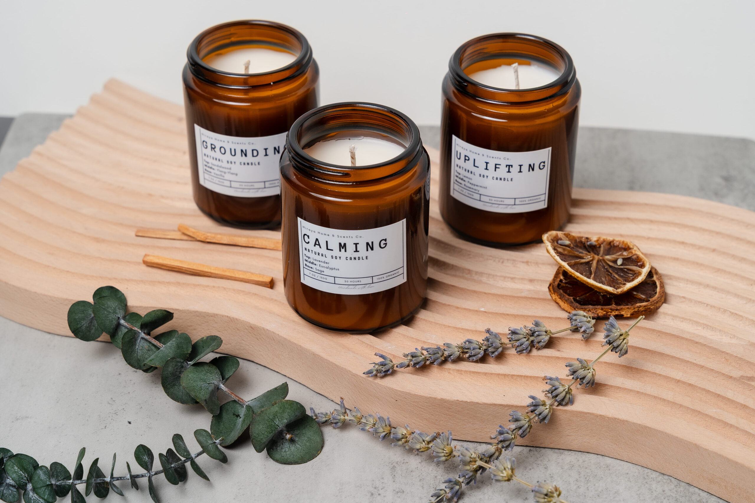 Group display of the Calming, Uplifting, and Grounding aromatherapy candles in amber jars.