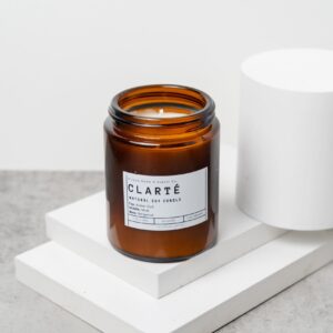 Front view of the Clarté candle with amber‑oud‑musk‑bergamot label in a 150ml jar.