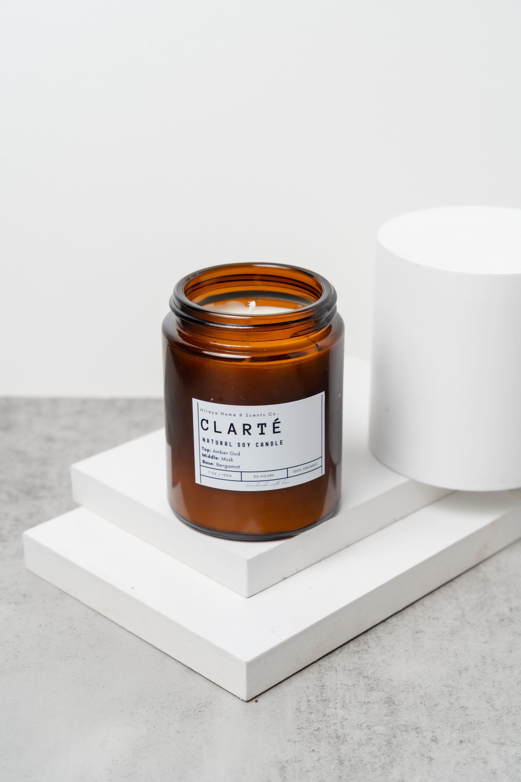 Front view of the Clarté candle with amber‑oud‑musk‑bergamot label in a 150ml jar.