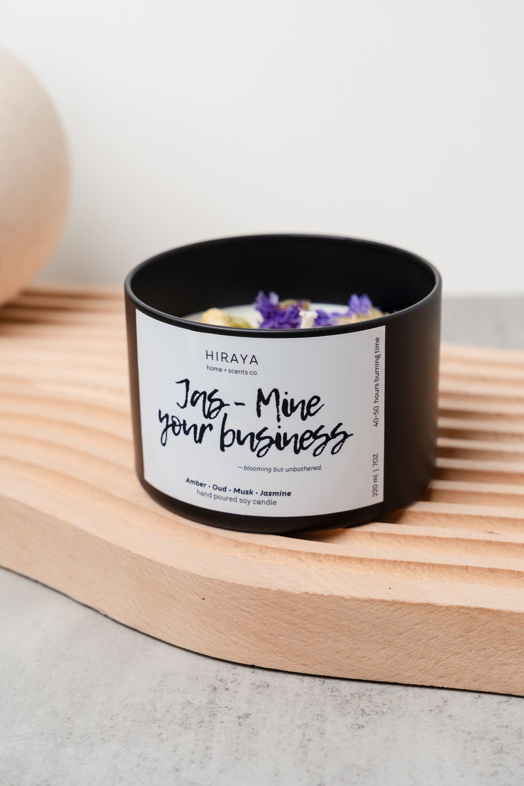 Front view of the Jas‑Mine Your Business candle with its amber‑oud‑jasmine label in a 220ml jar, styled in a soft, feminine aesthetic.