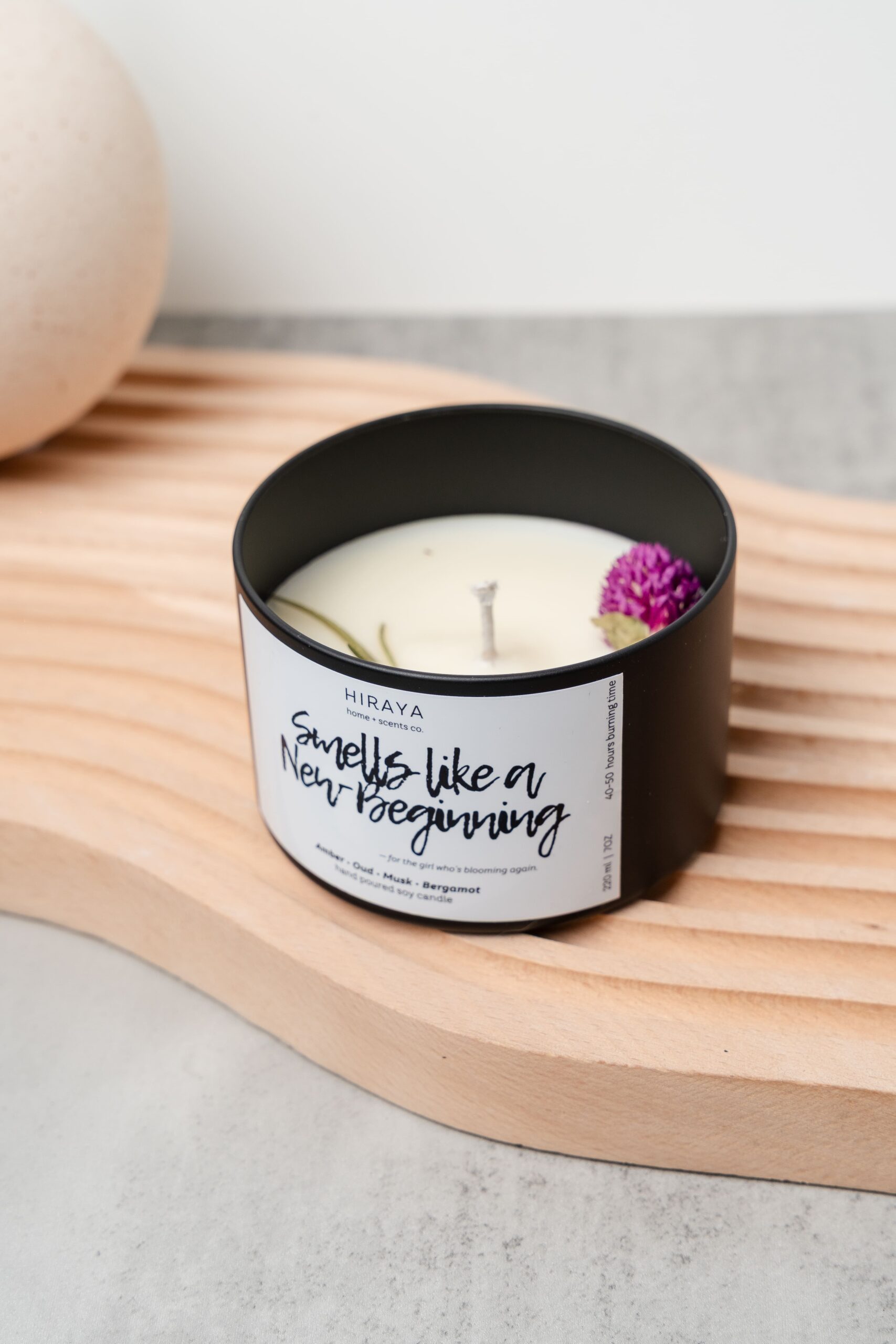 Front view of the Smells Like New Beginning candle with its amber‑oud‑bergamot label in a 220ml jar, styled in a clean, modern aesthetic.